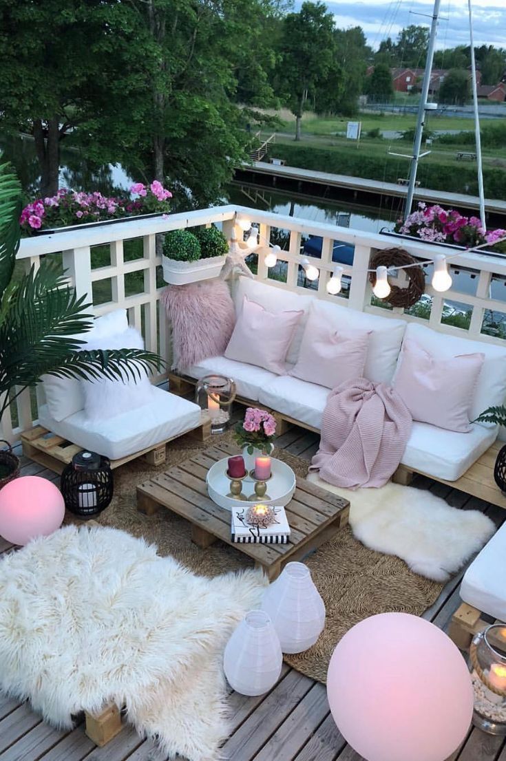 an outdoor living area with white furniture and pink pillows