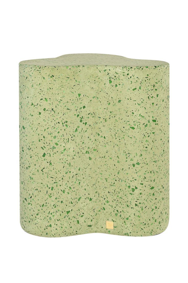 a green vase sitting on top of a white surface with lots of small speckles