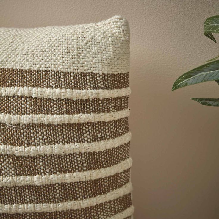 a brown and white pillow sitting next to a potted plant