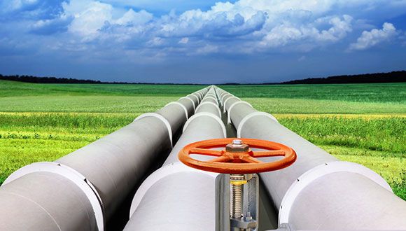 an oil pipeline in the middle of a green field with blue sky and clouds above it