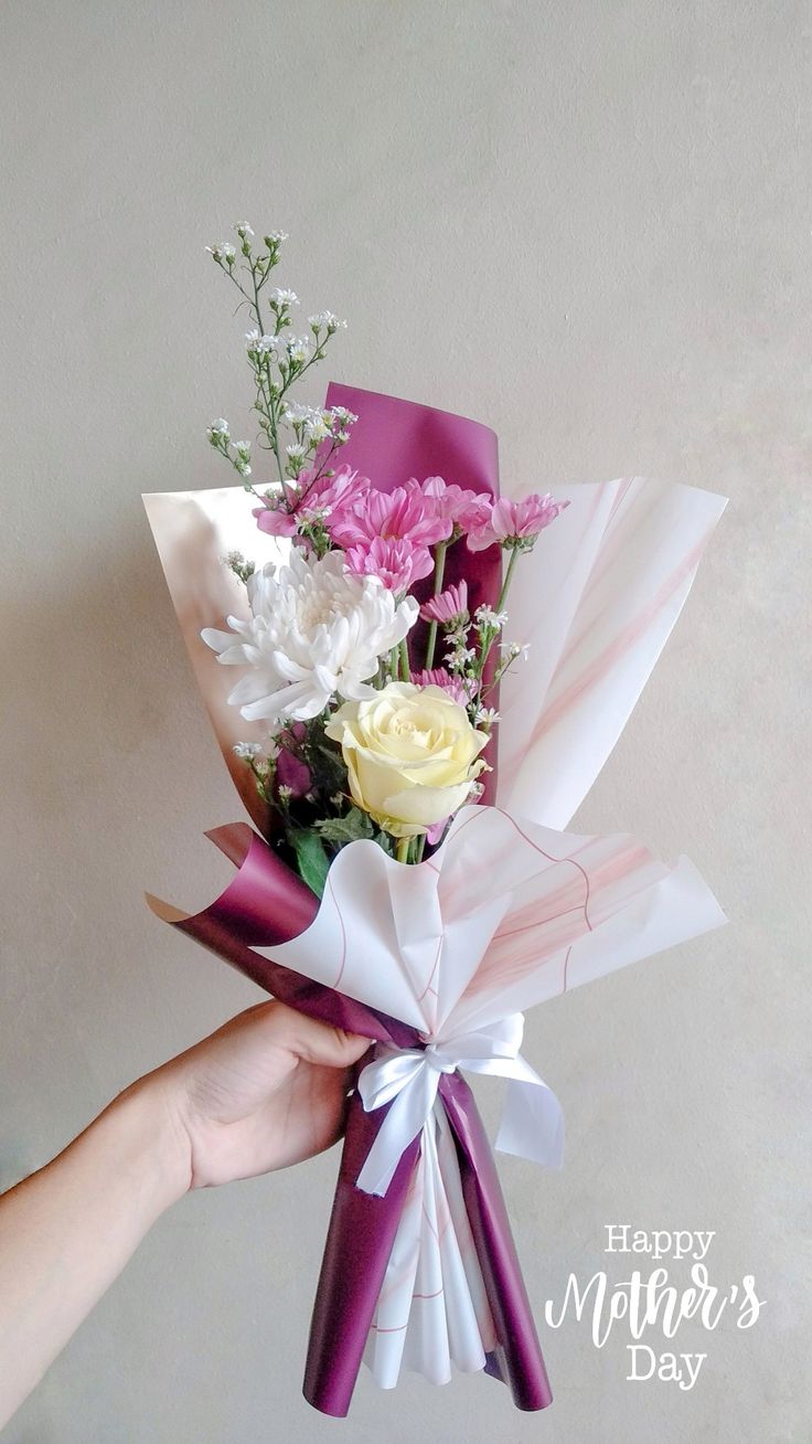 a person holding a bouquet of flowers in their hand with the words happy mother's day written on it