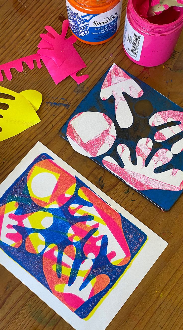 paper cut outs and paint sitting on top of a wooden table