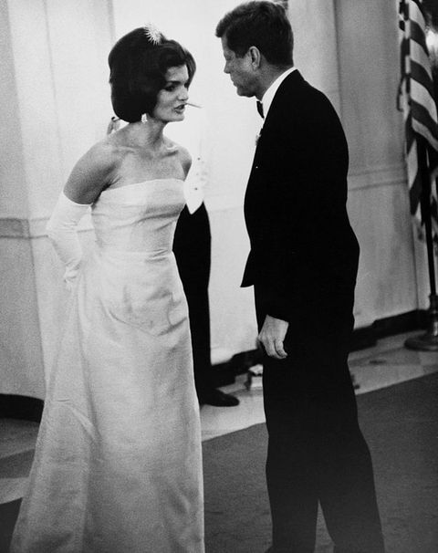 a man in a suit and tie standing next to a woman in a white dress