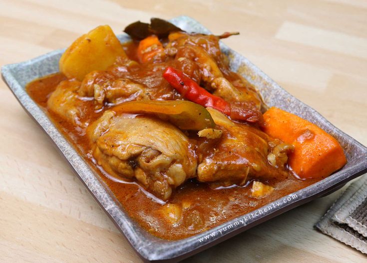 a plate full of meat and vegetables on top of a wooden table next to napkins