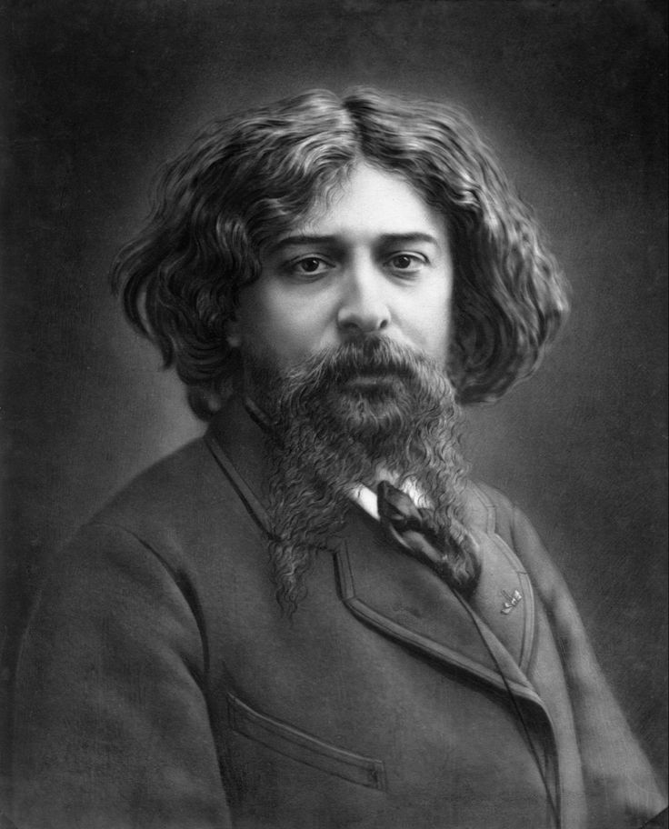 an old photo of a man with long hair and a beard wearing a suit jacket