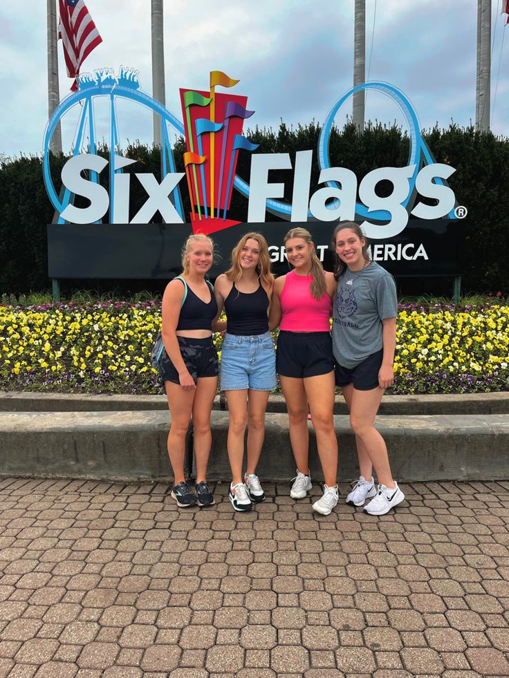 four girls posing in front of six flags sign