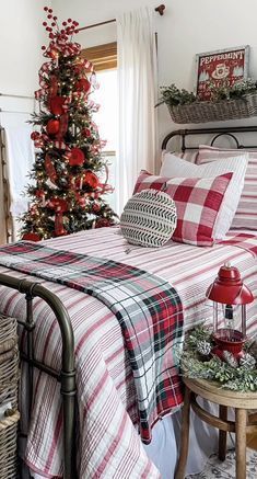 a bedroom decorated for christmas with plaid bedding and red decorations on the side table