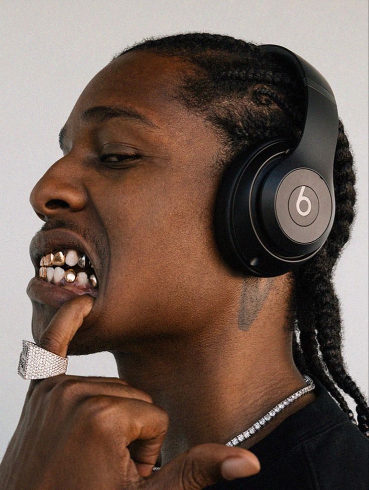 a man with dreadlocks and headphones on his face is brushing his teeth