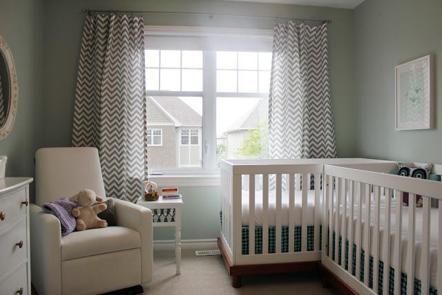 a baby's room with a crib, chair and window