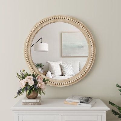 a living room with a white dresser and round mirror on the wall above it, along with a potted plant