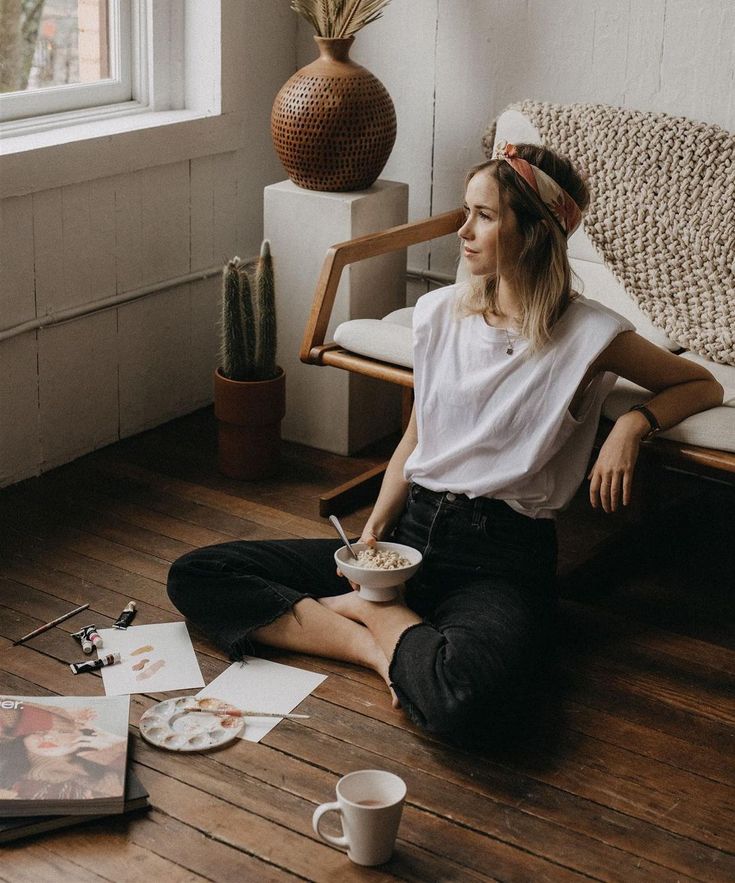 a woman sitting on the floor eating cereal