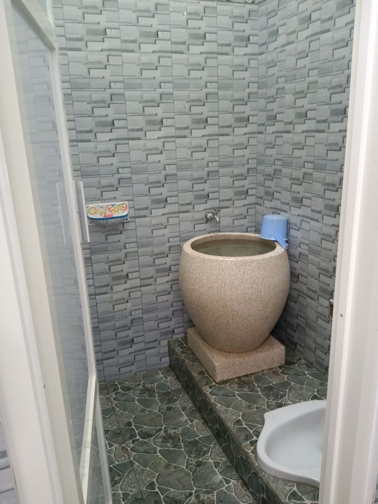 a bathroom with a toilet, sink and tiled walls in it's stall area