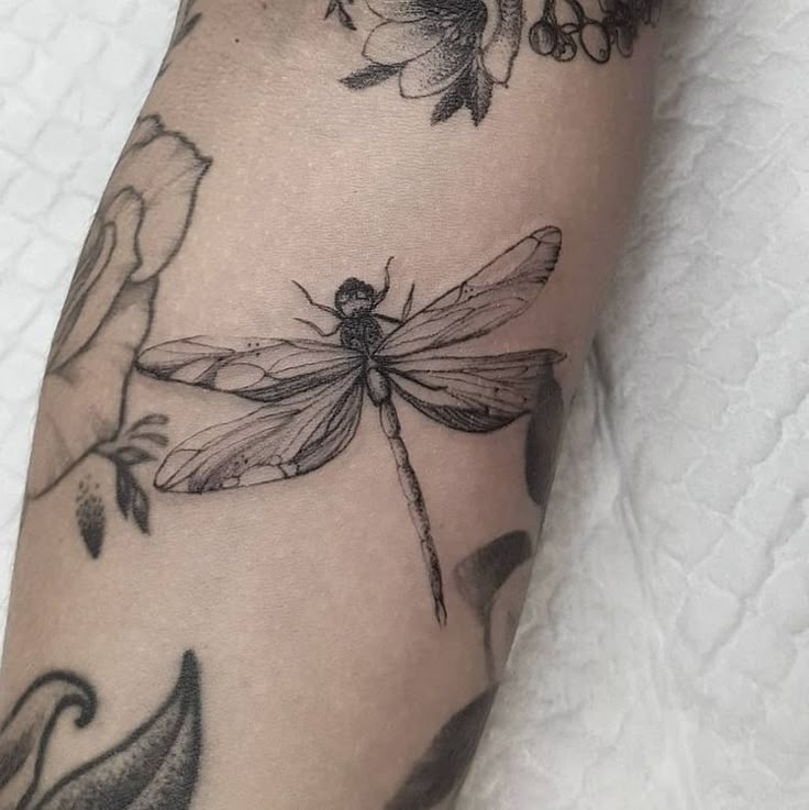 a woman's leg with tattoos on it and a dragonfly sitting on top