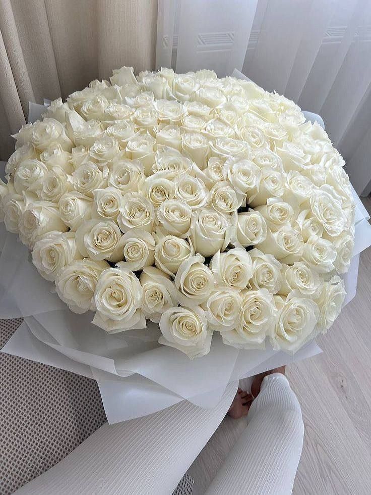 a large bouquet of white roses sitting on top of a chair next to a window