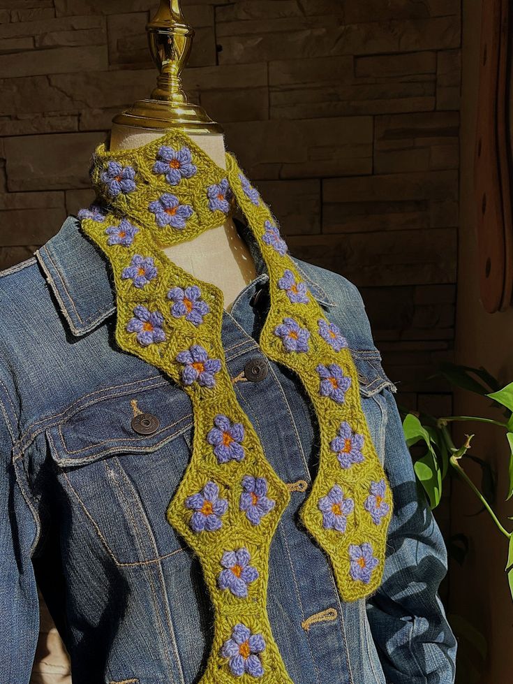 a crocheted neck tie on a mannequin wearing a denim shirt and jean jacket