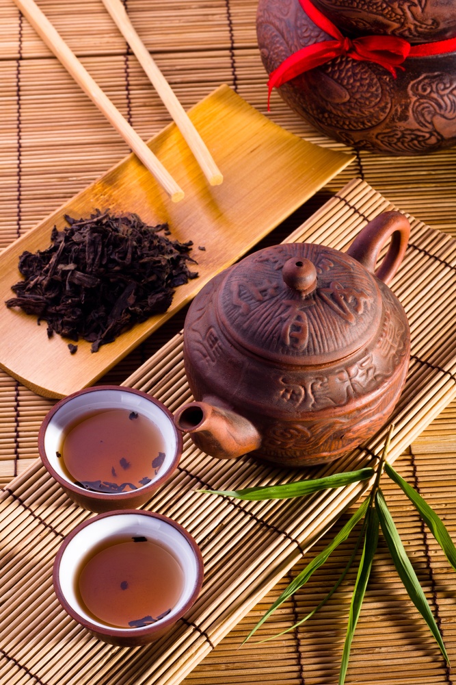 two cups of tea and three spoons on bamboo mat with chopsticks - stock photo