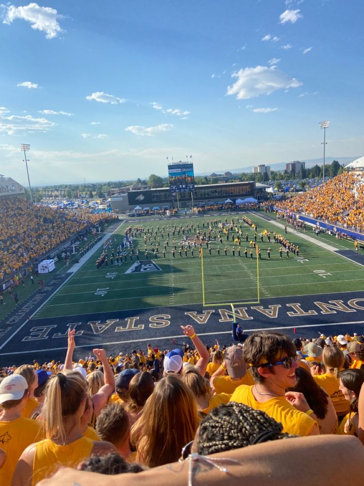 a football stadium filled with fans and cheerleaders watching the game from the bleachers