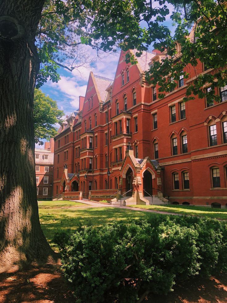 an old red brick building in the middle of a park with trees and bushes around it