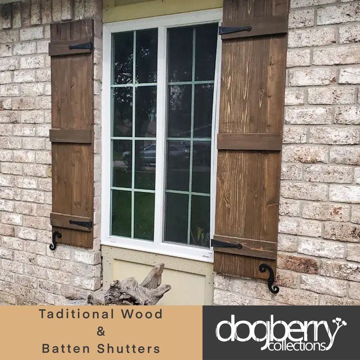 two windows with wooden shutters on the side of a brick building