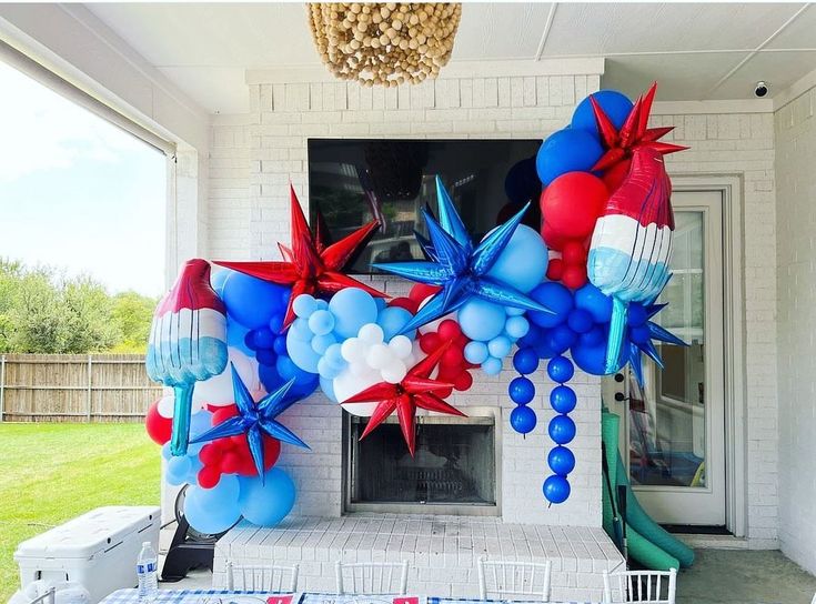 an outdoor party with balloons and streamers on the front porch, decorated for fourth of july