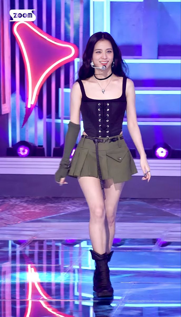 a woman is walking down the runway in a short skirt and black top with buttons on it