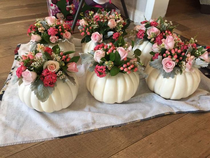 four white pumpkins decorated with flowers on a table