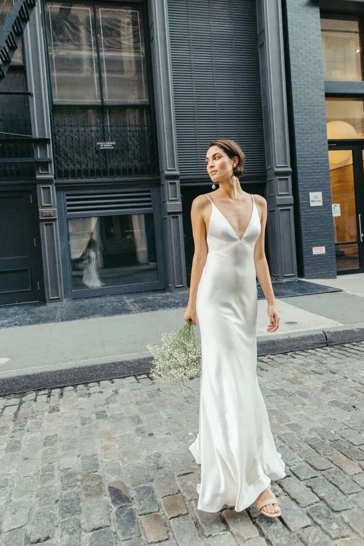 a woman in a white dress is walking down the street