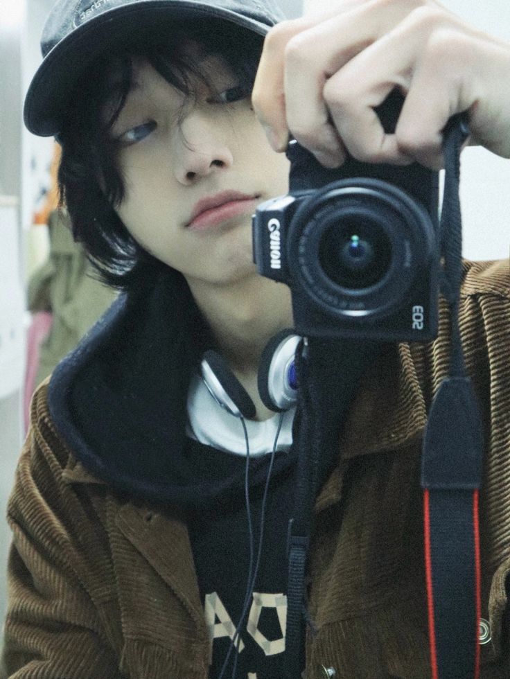 a young man holding up a camera to take a selfie in front of him