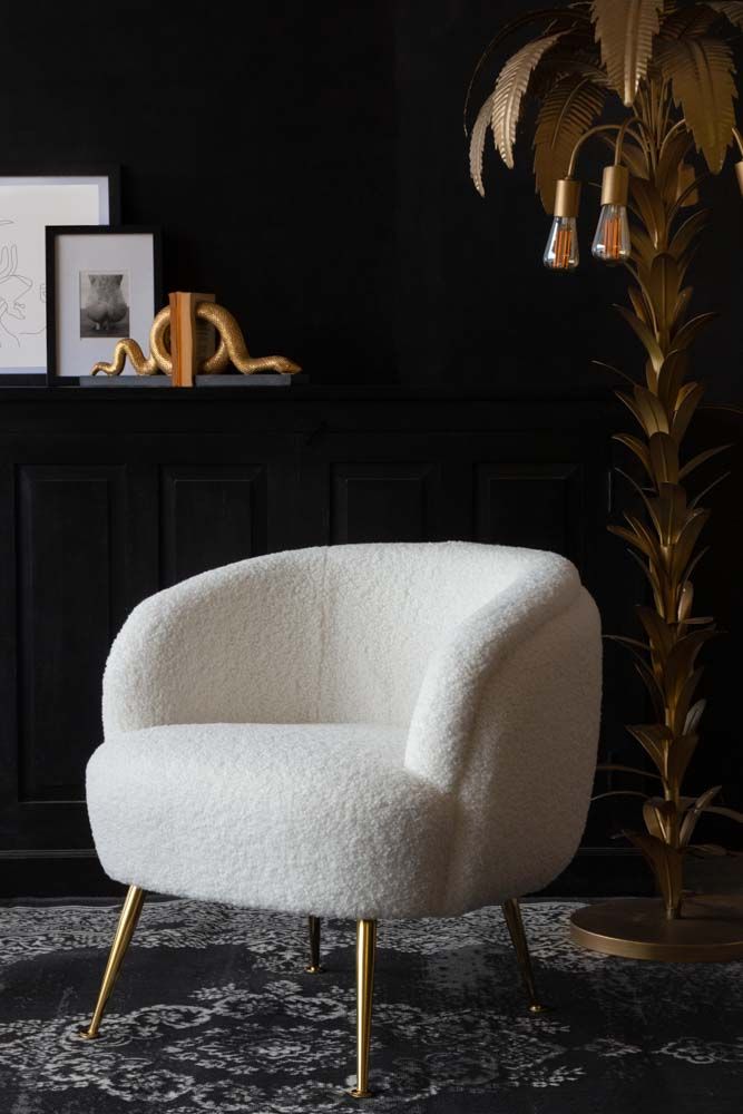 a white chair sitting on top of a rug next to a tall plant in a living room