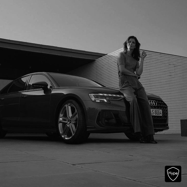 a woman sitting on the hood of a car next to a black and white photo