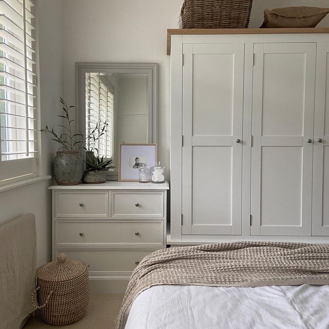 a bedroom with white cupboards and drawers in it