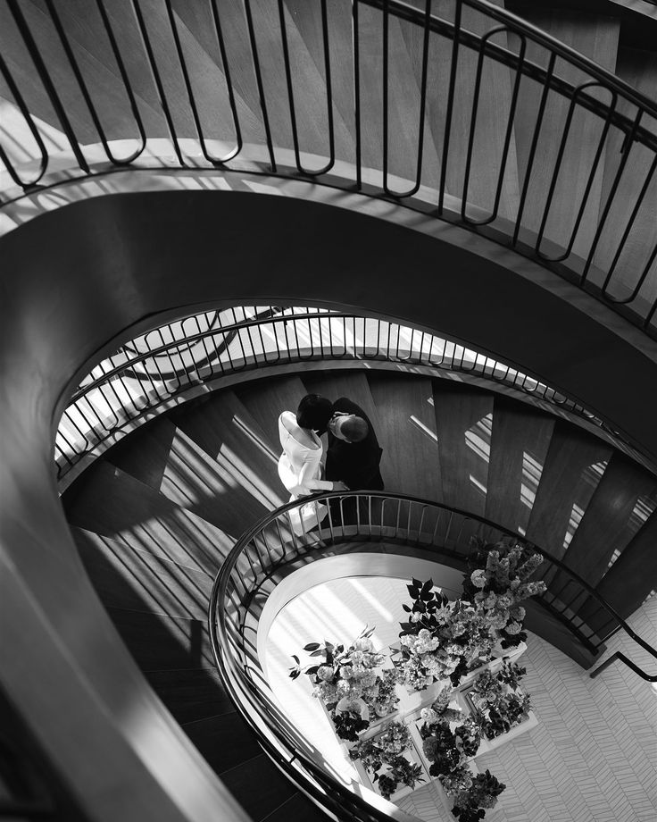 two people are standing at the top of a spiral staircase in black and white photo