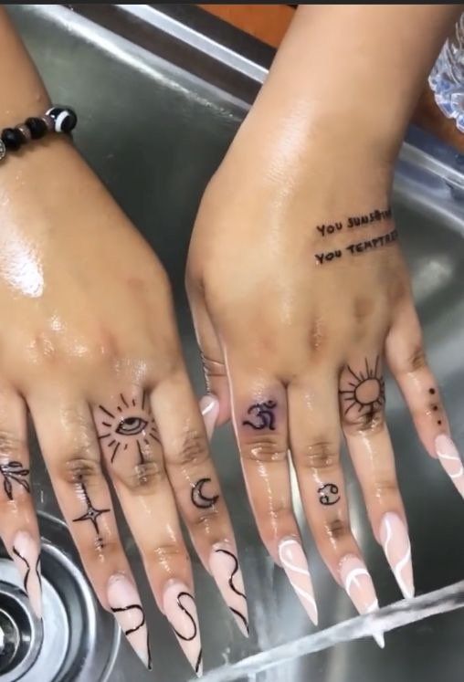 two hands with tattoos on them sitting next to a sink