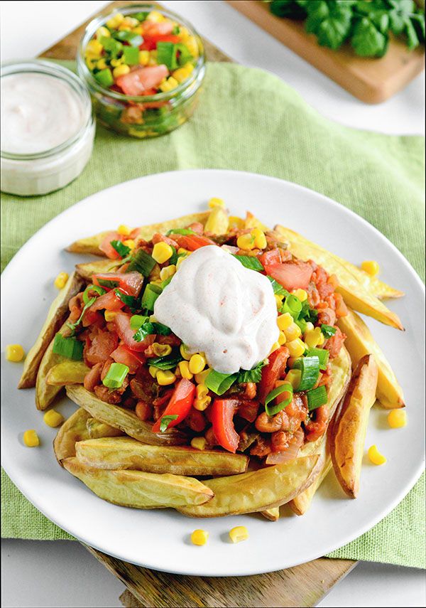 a white plate topped with french fries covered in salsa and sour cream next to a jar of ranch dressing