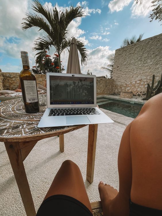 a person sitting at a table with a laptop and bottle of wine in front of them