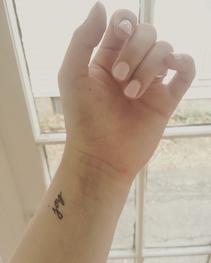 a woman's hand with a small tattoo on it, in front of a window