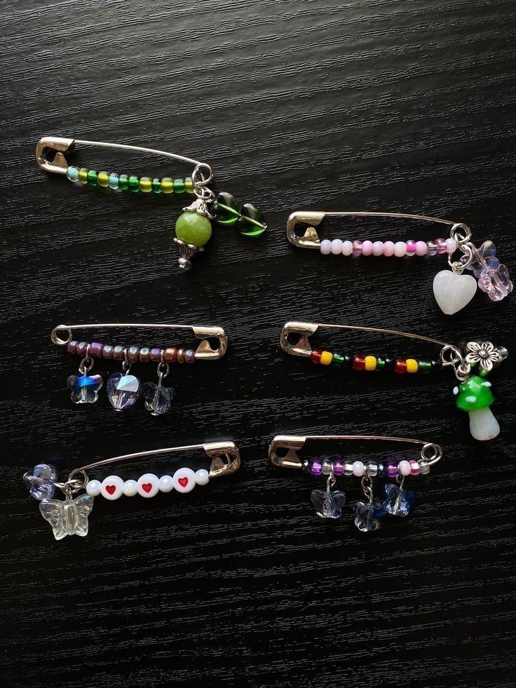 six hair pins with charms on them sitting on top of a wooden table next to each other