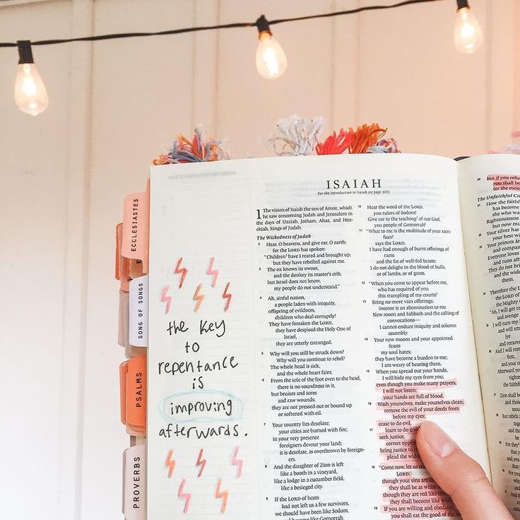 an open book with writing on it in front of some light bulbs and string lights