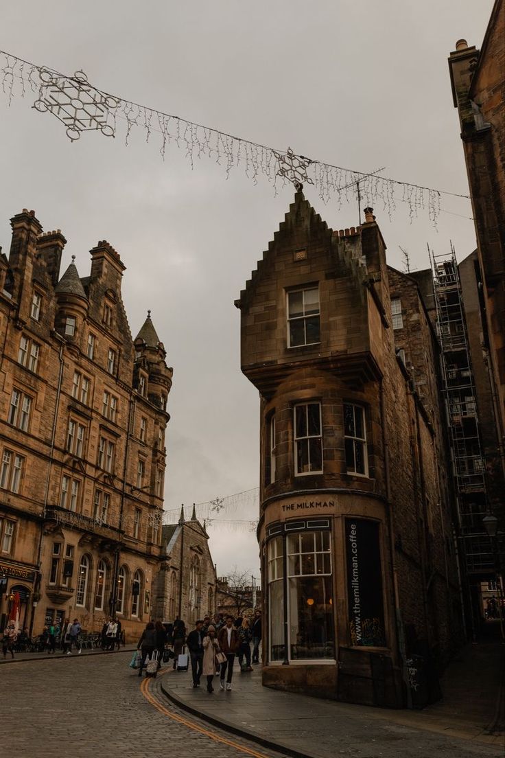 people are walking down the street in front of some old buildings on a cloudy day