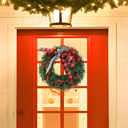 a red door with a wreath hanging on it's side and lights in the background