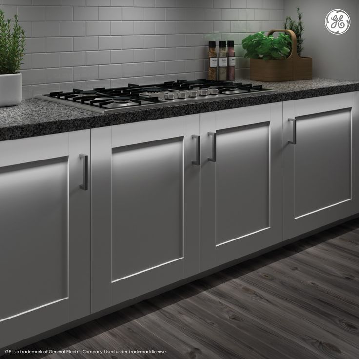 an image of a kitchen setting with white cabinets and black counter tops on wood flooring