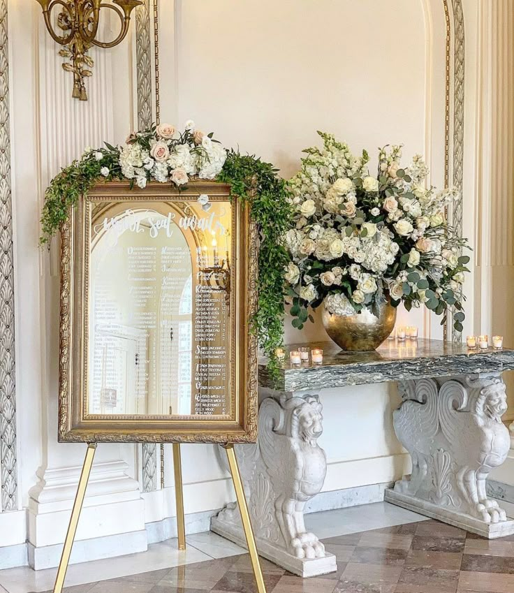 there is a mirror and vase on the table with flowers in front of it, along with other decorations