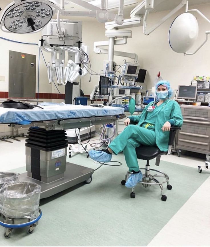 an operating room with medical equipment and people in scrubs sitting on chairs around the table