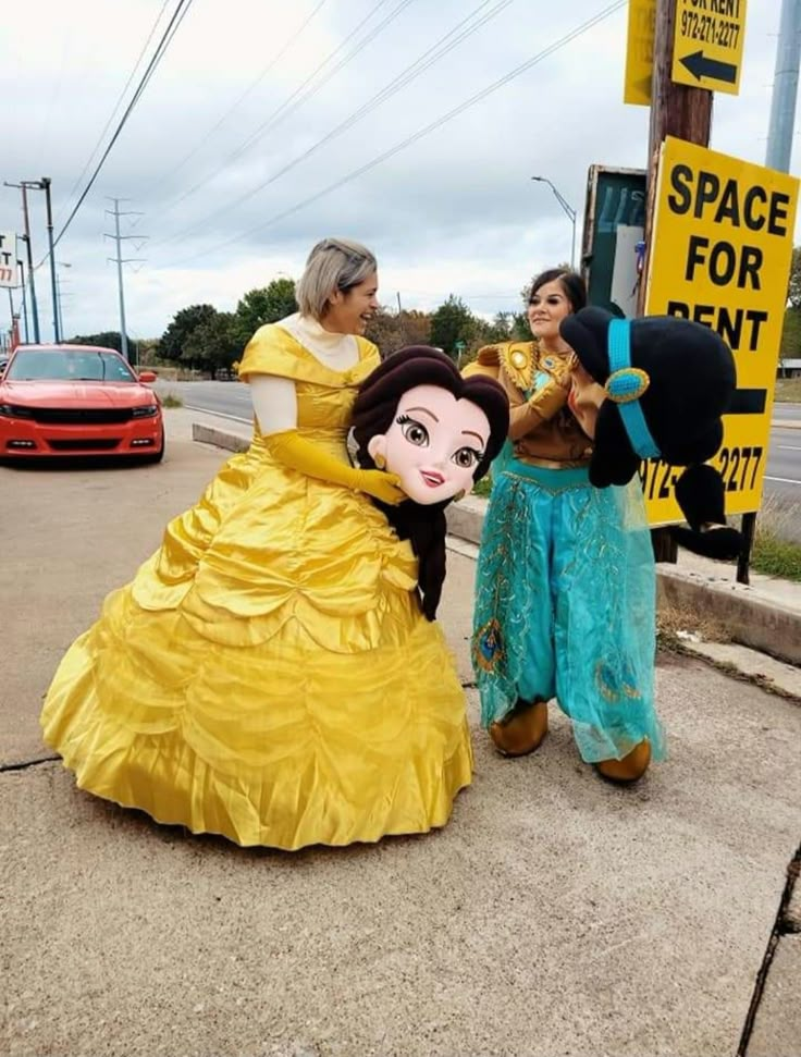 two people dressed up as disney and princesses on the side of the road in front of a sign that says space for rent