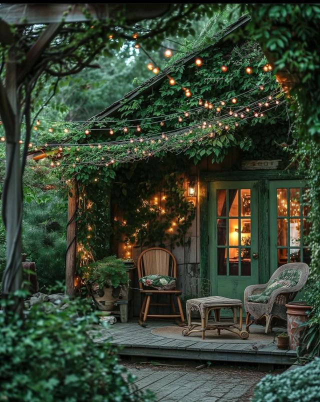 an outdoor patio with chairs and lights strung over the door, surrounded by greenery