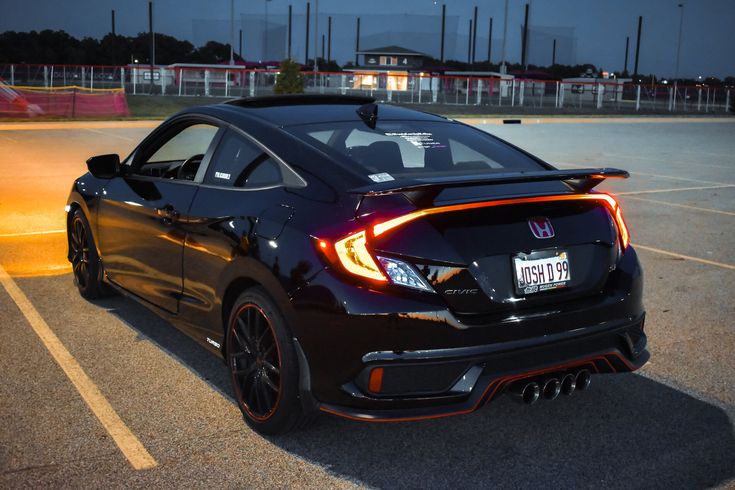 a black car parked in a parking lot with its lights on and the hood up