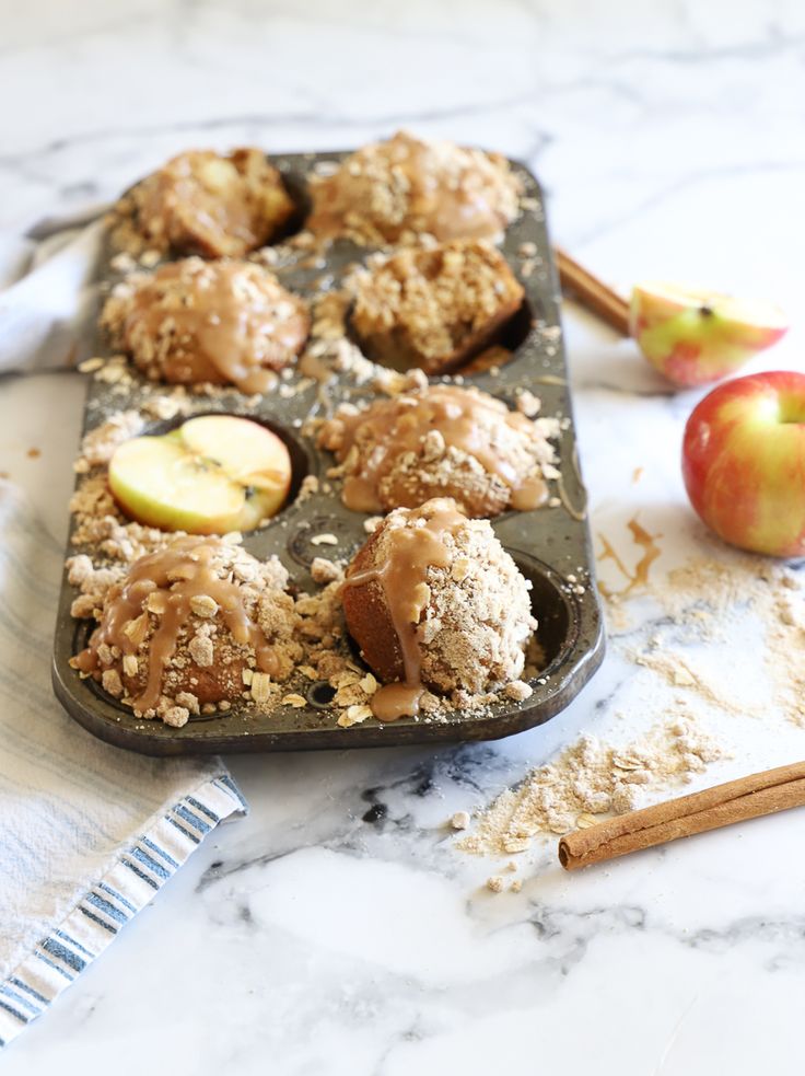 muffins and apples on a baking tray with cinnamon sticks, an apple in the background