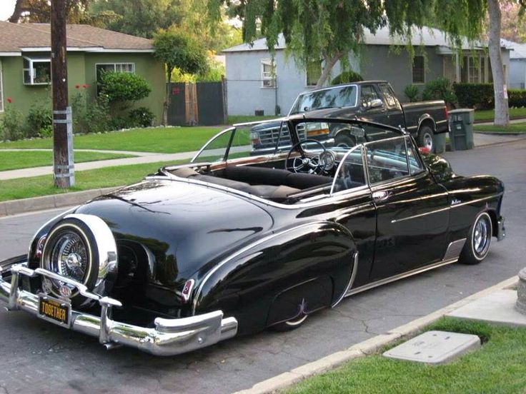 an old car is parked on the side of the road in front of a house