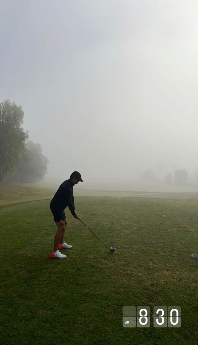 a man playing golf on a foggy day