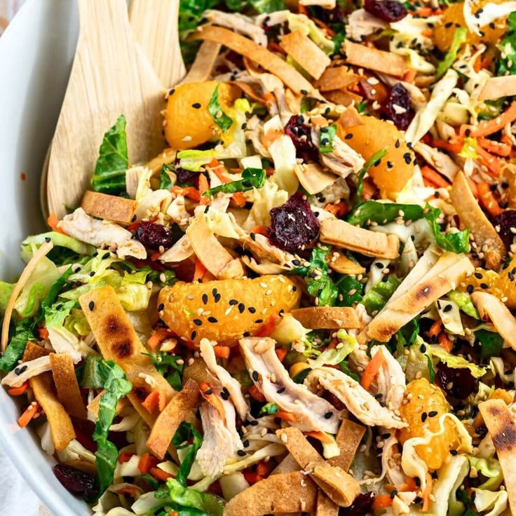 a salad with chicken, carrots and cranberries in a white bowl